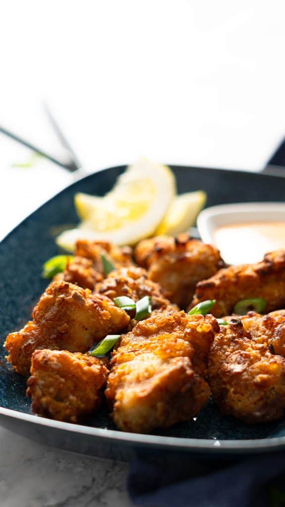 Air fryer karaage on a plate with lemon wedges and sriracha mayo