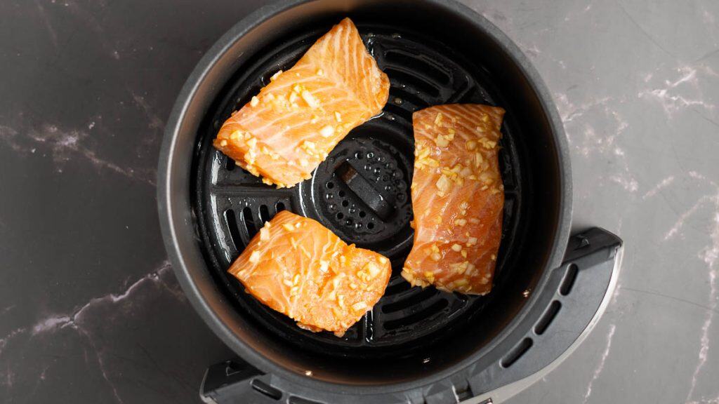 Raw marinated salmon in an air fryer basket