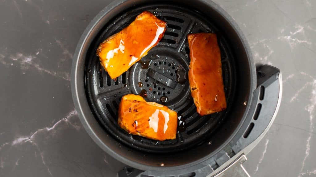Salmon coated in teriyaki sauce in an air fryer basket