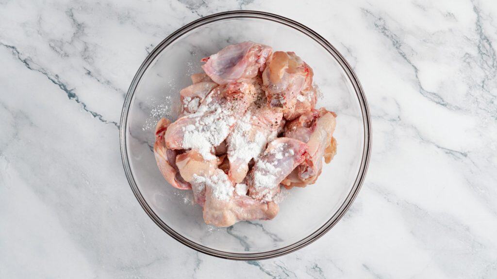 Raw chicken wings with baking powder, black pepper and salt on top