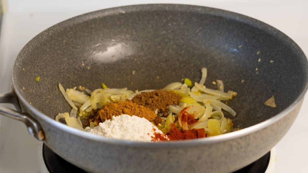 Flour and spices added to onions in a pan