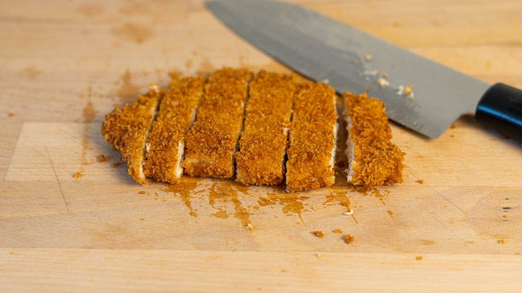 Pork katsu sliced into strips on a cutting board