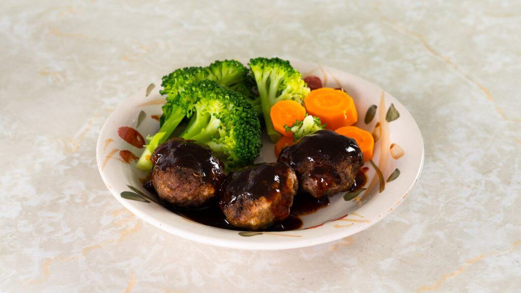 Japanese Hamburg steak with sauce on top and broccoli and carrots on the side