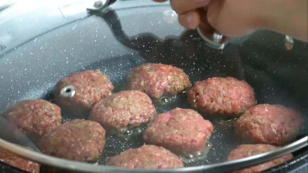 Japanese Hamburg steaks in a skillet covered with a lid