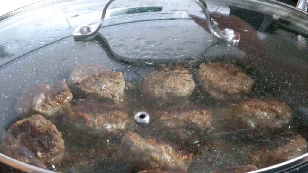 Japanese Hamburg steaks in a skillet with lid covered