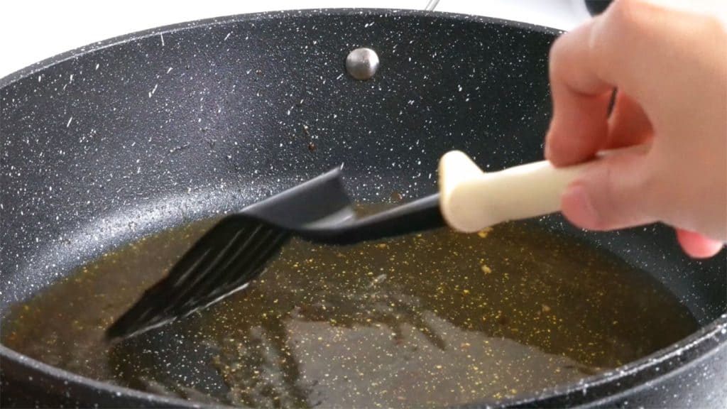 Stirring sake with spatula in skillet to deglaze