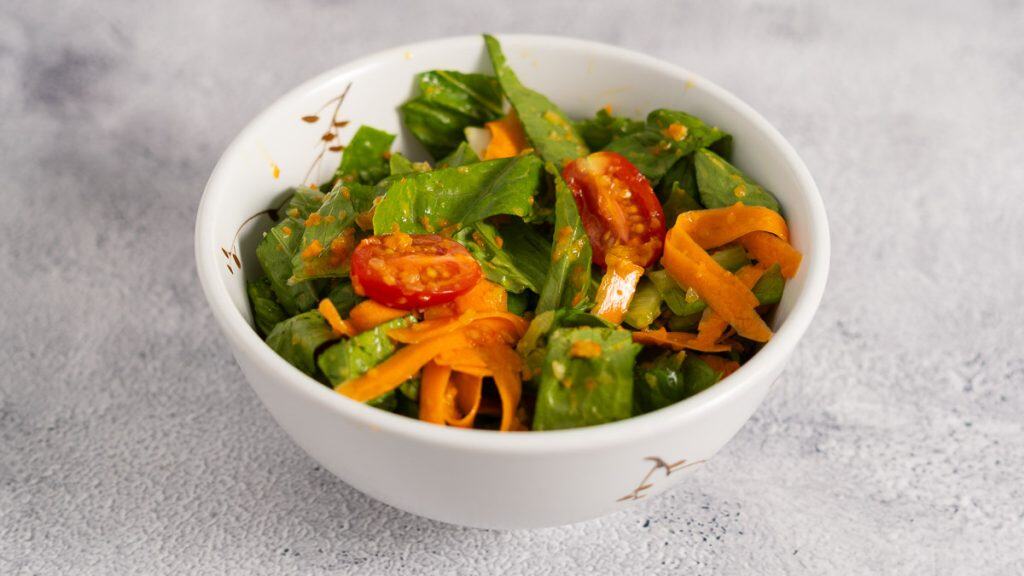 Japanese style salad with chopped romaine lettuce, grape tomatoes and carrot in a white bowl