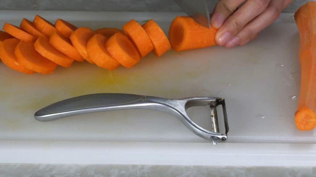 Chopping carrot into coins on a white cutting board