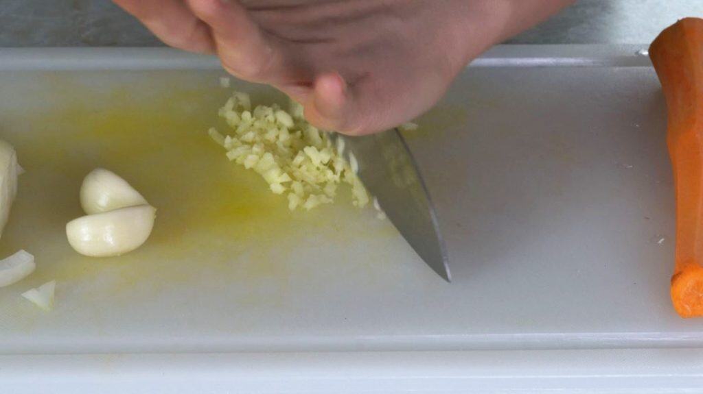 Mincing ginger on a white cutting board