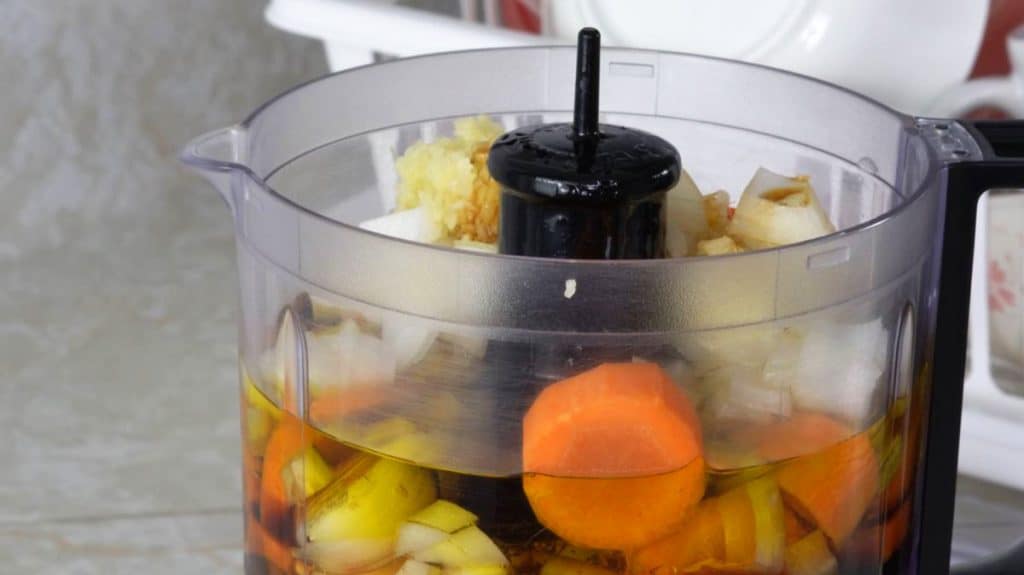Food processor with carrots, olive oil, onion, ginger and honey in it
