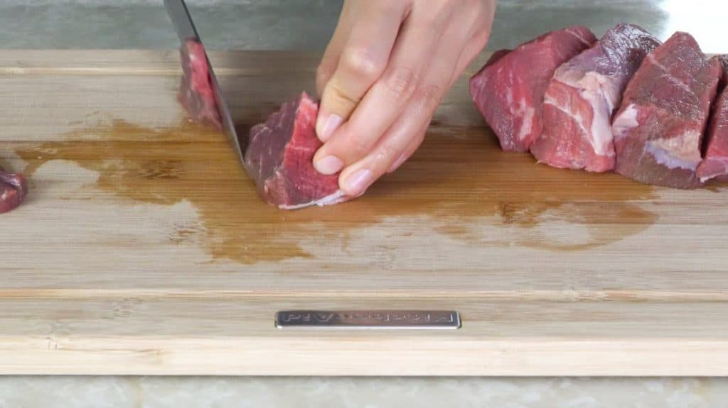 Slicing beef sirloin against the grain on a wooden cutting board