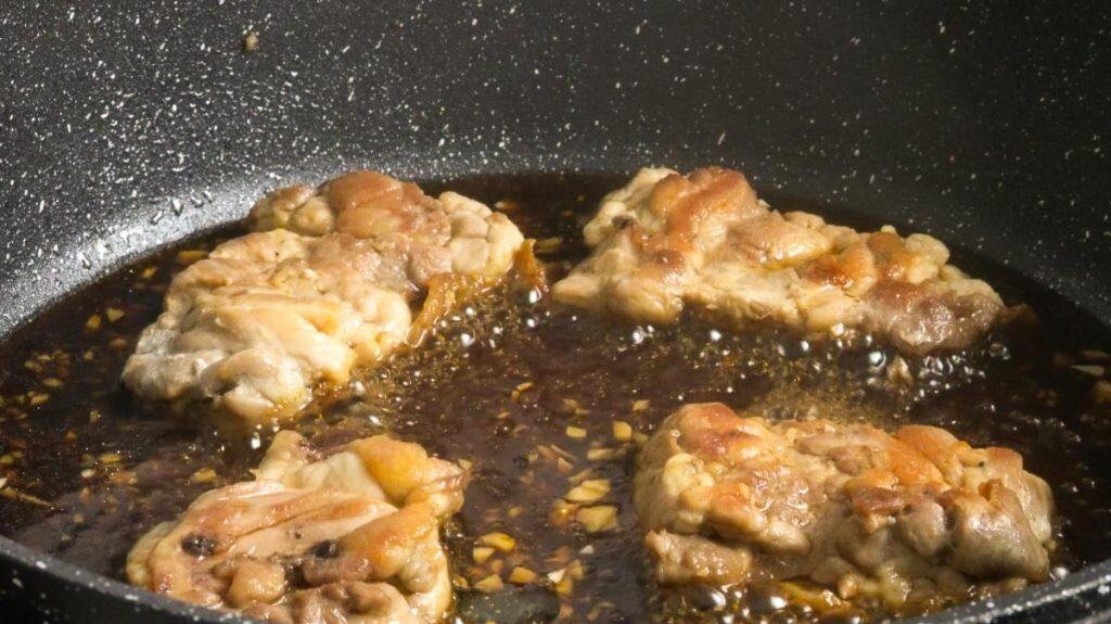 Reducing teriyaki sauce while simmering chicken thighs in teriyaki sauce in a non-stick pan