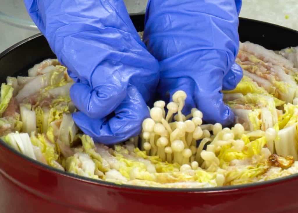Placing enoki mushrooms in the center of mille feuille nabe in a Dutch oven