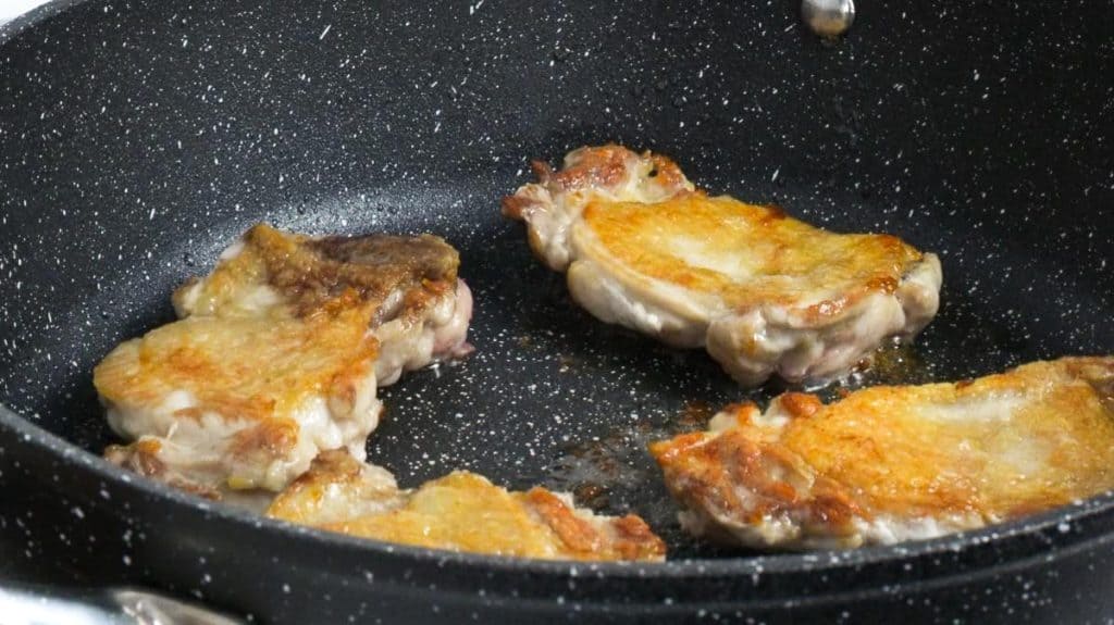 Frying skin-on chicken thighs on a non-stick pan