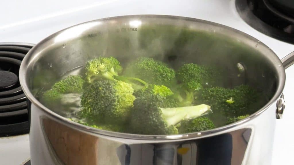 Boiling broccoli in a stainless steel saucepan over an electric stove