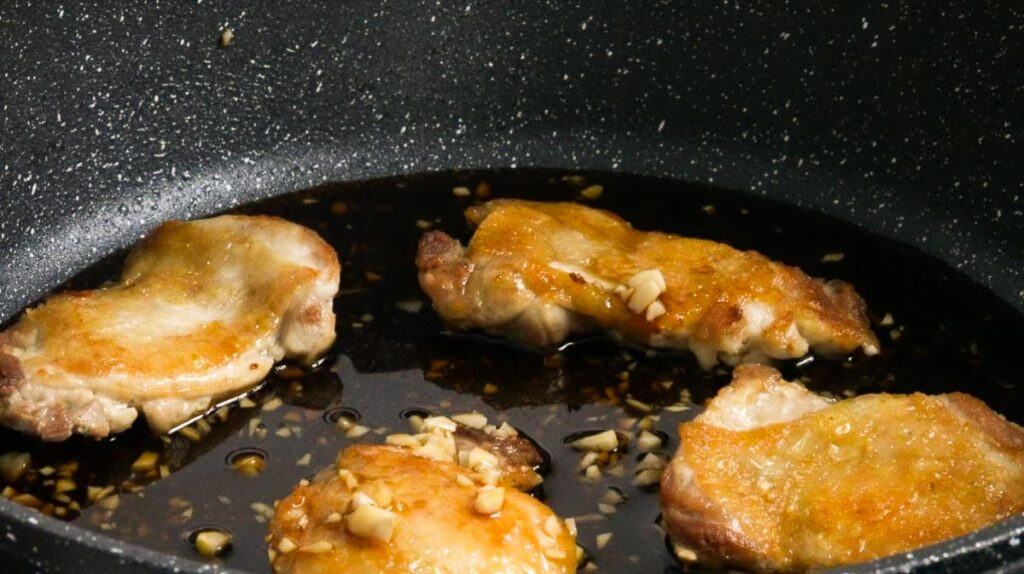 Simmering chicken thighs in teriyaki sauce in a non-stick pan