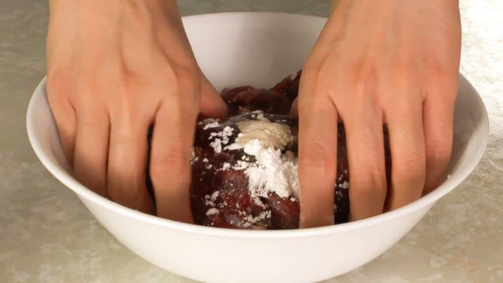 Mixing sliced beef with marinade ingredients with bare hands