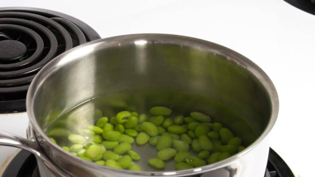Boiling edamame in a stainless steel saucepan on an electric stove