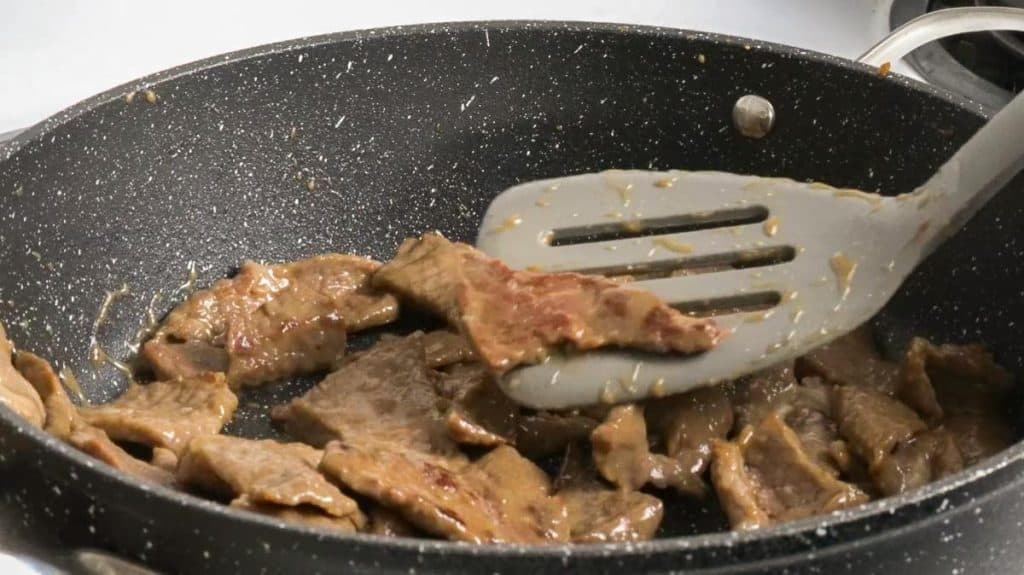 Cooked, sliced beef sirloin on a non-stick pan with a spatula
