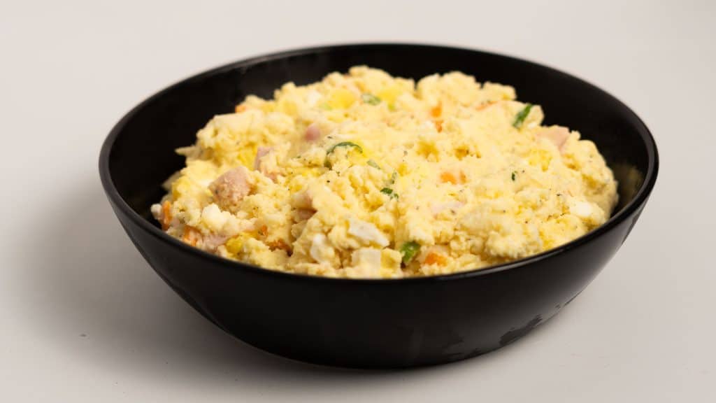 Japanese potato salad with potato, carrot, ham, green onion and egg in a black bowl