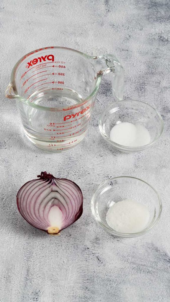Ingredients for pickled red onions, including half a red onion, vinegar, salt and sugar