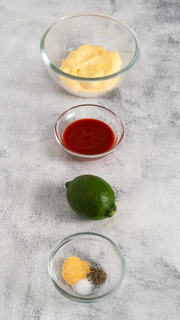Ingredients for spicy mayo, including kewpie mayo, sriracha, lime, garlic powder, black pepper and salt