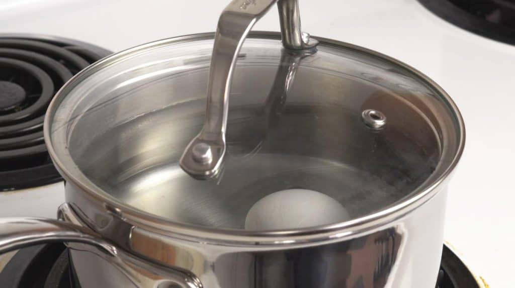 Boiling white eggs in a stainless steel saucepan on an electric stove