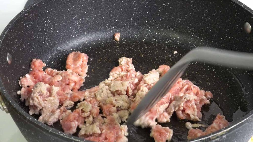 Cooking ground pork in a pan with a spatula
