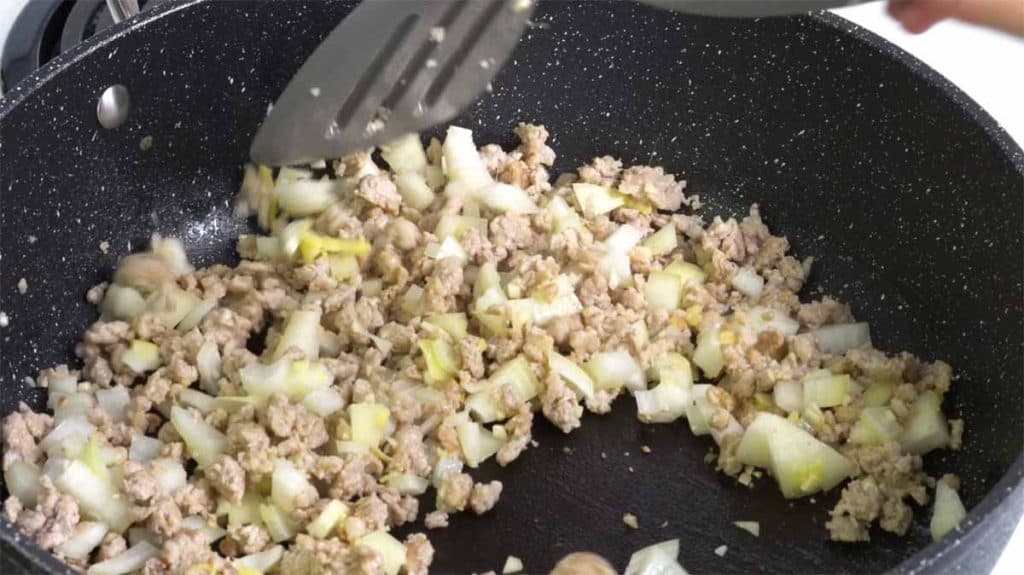 Frying minced garlic, ginger and onion with ground pork in a pan
