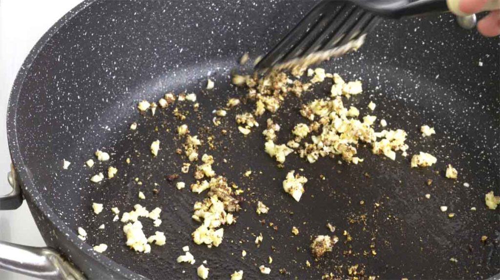 Pan frying minced garlic and ground Sichuan peppercorns