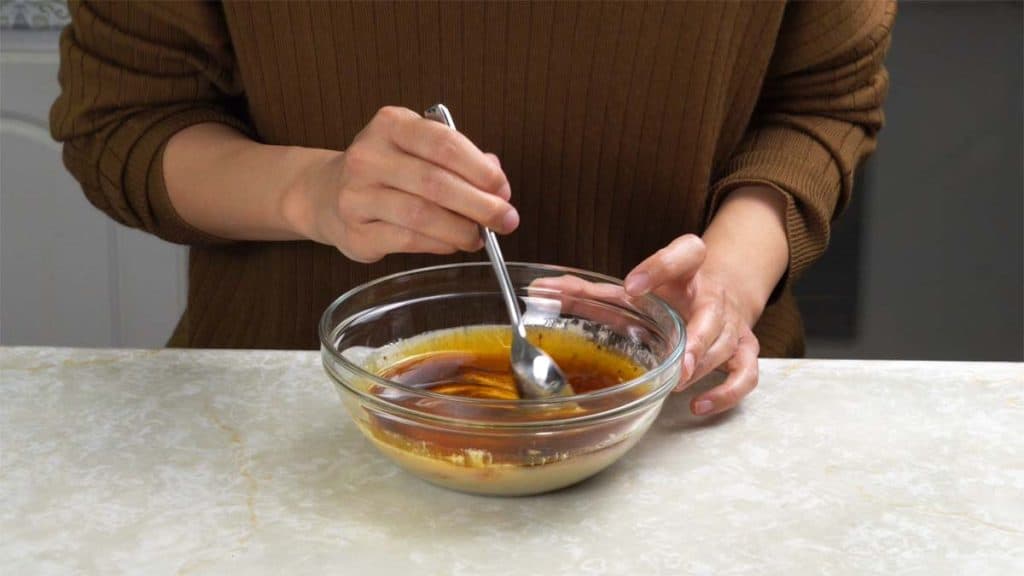 Mixing spicy sauce in a small glass bowl with a spoon