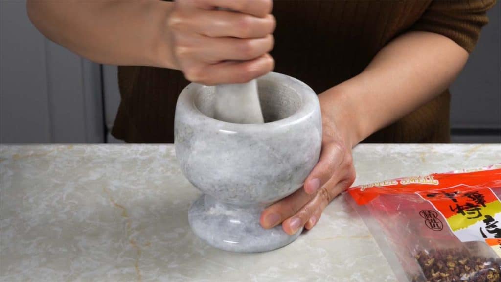 Grinding Sichuan peppercorns with a mortar and pestle