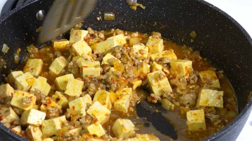 Stirring in cornstarch slurry into mapo tofu in a pan