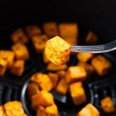 Air fried seasoned diced sweet potato in an air fryer basket