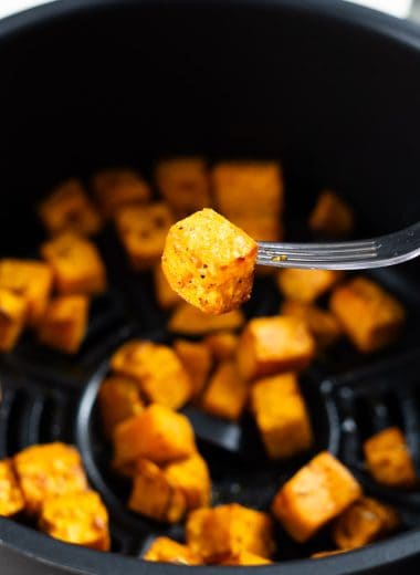 Air fried seasoned diced sweet potato in an air fryer basket