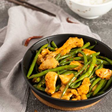 Spicy chicken and green beans stir fry with a bowl of steamed rice