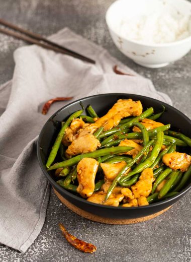 Spicy chicken and green beans stir fry with a bowl of steamed rice